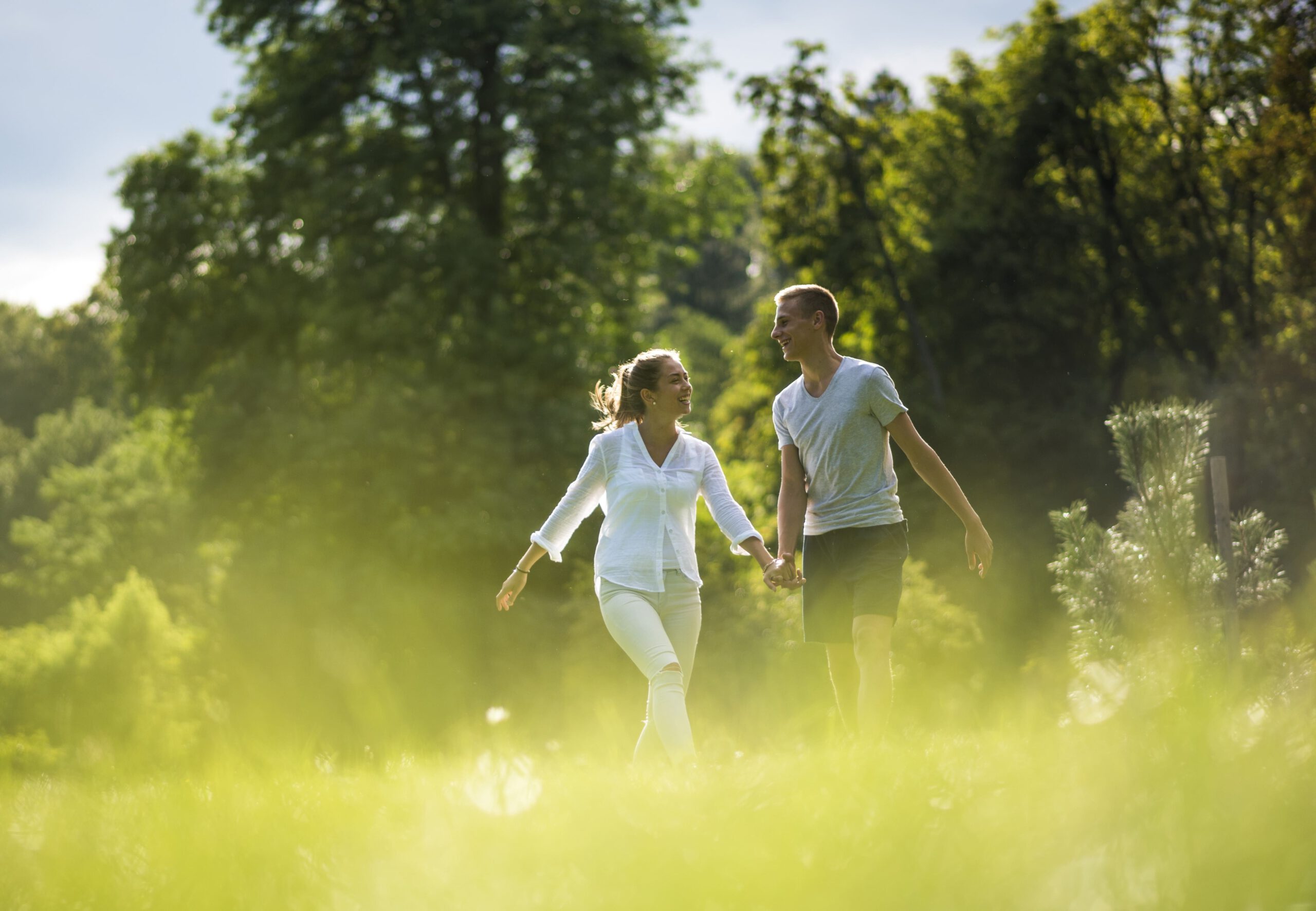 Two people walking in an environment full of trees and plants