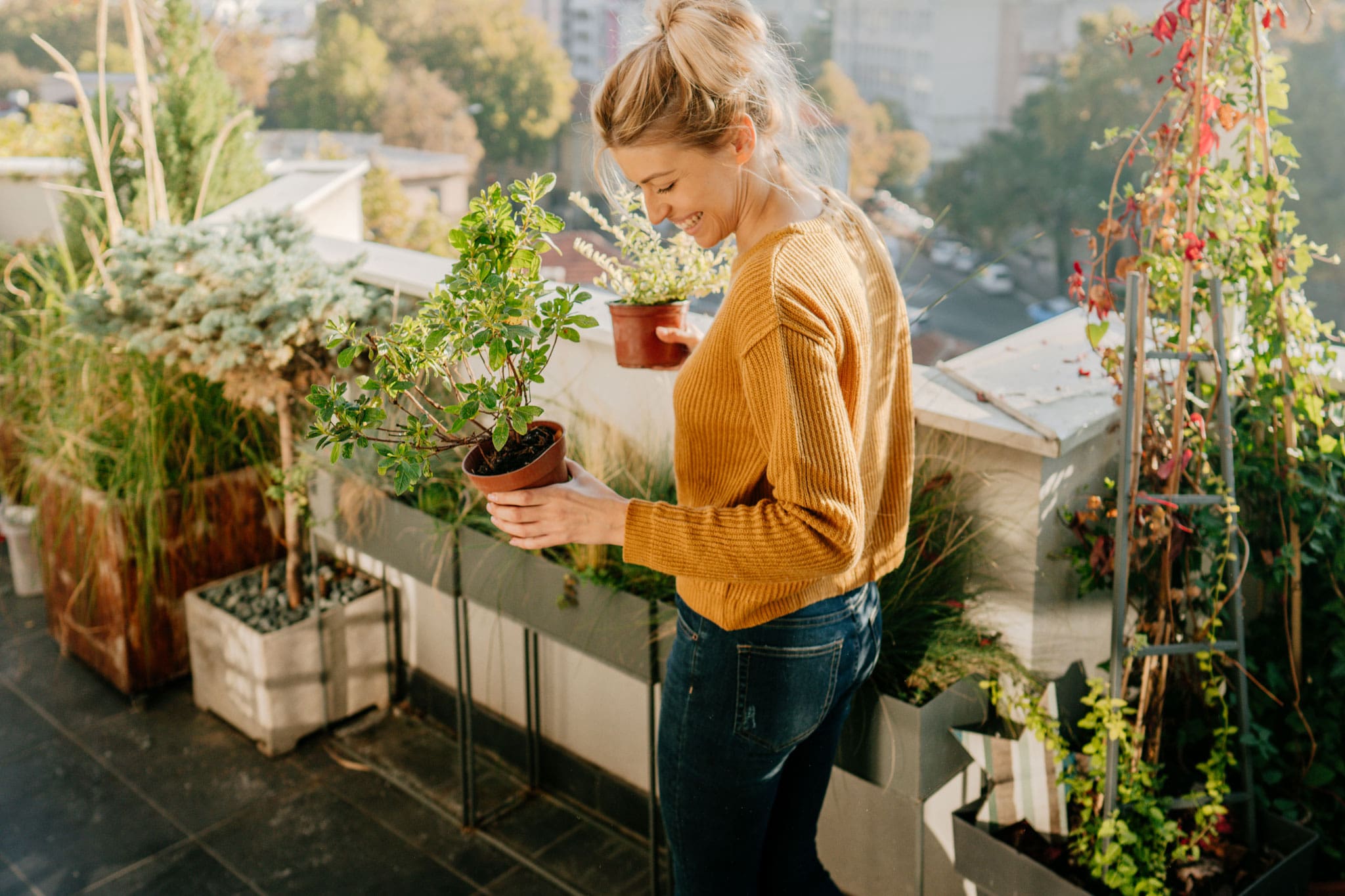A woman standing in a space full of plants looking happy